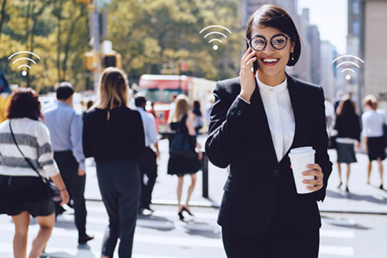 Une femme parlant au téléphone et marchant dans la rue, connectée au Wi-Fi